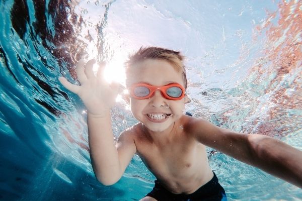niño 6 años riendo por aprender a nadar